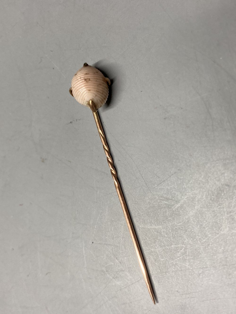 A cased early 20th century yellow metal and carved sardonyx set stick pin, 8cm and a similar shell stick pin, 56mm.